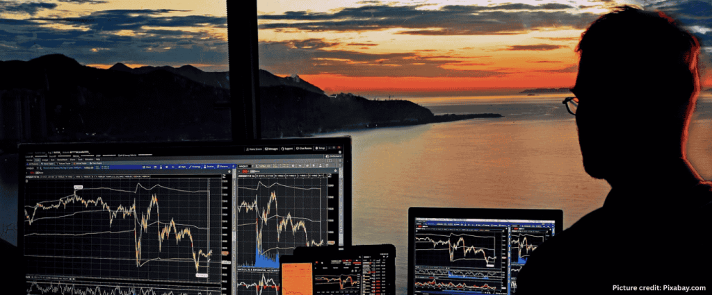 Trader with multiple screens open looking out onto a sunset